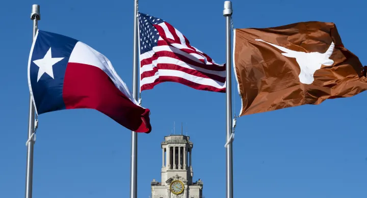 Image of US, Texas, and UT flags flying with UT Tower in background
